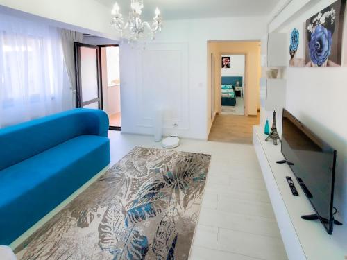 Una sala de estar con un sofá azul y una alfombra. en Unique Hotel Apartments Iasi, en Iaşi