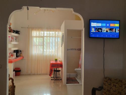 a living room with a table and a tv on the wall at Amalfi's Place in Pimentel