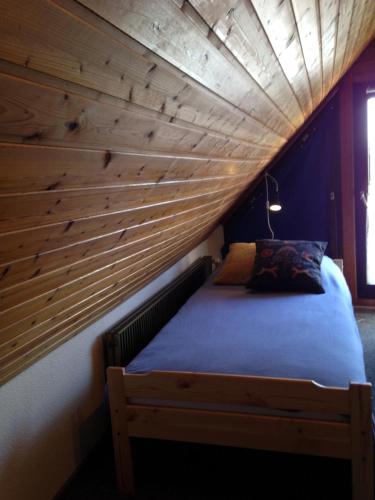 a bed in a room with a wooden wall at Gemütliches Ferienhaus Mainz in Mainz