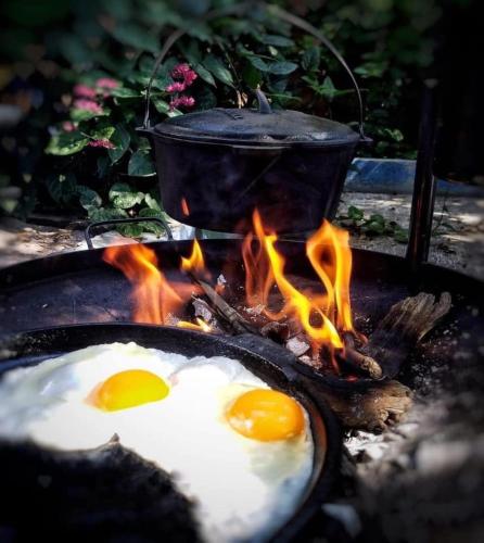 two fried eggs cooking on a grill with a pot at La Casita Inn Bustamante in Bustamante