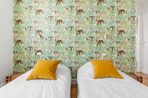Duas camas com almofadas amarelas num quarto com papel de parede em Bel appartement avec garage sur l'île de Nantes em Nantes