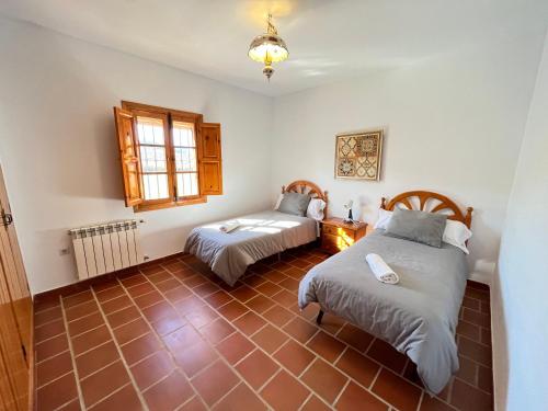 a room with two beds and a window at Casa Rural Huerta Abuela María in Archidona