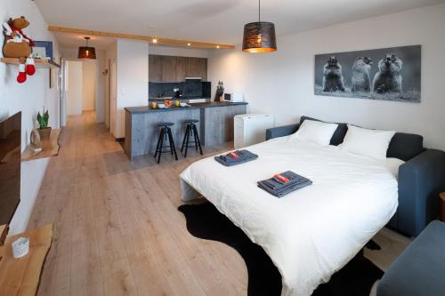 1 Schlafzimmer mit einem großen weißen Bett und einer Küche in der Unterkunft Magnifique appartement proche du centre et du ski in Crans-Montana