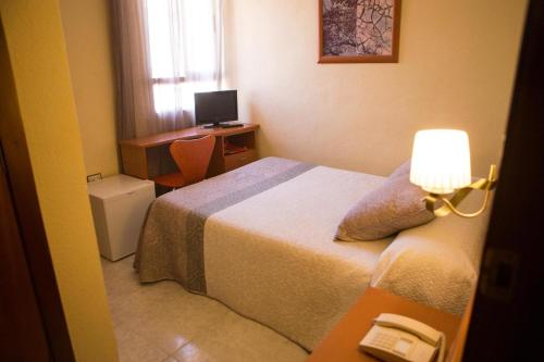 a bedroom with a bed and a desk with a computer at Hotel Madrid in Santiago de la Ribera