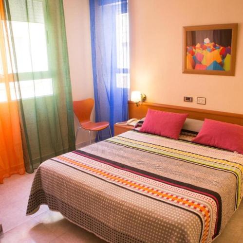a bedroom with a large bed with two red pillows at Hotel Madrid in Santiago de la Ribera