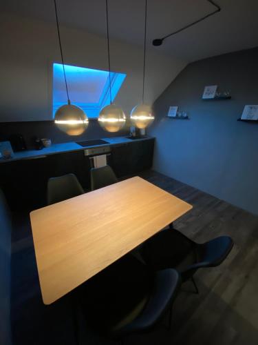 a wooden table with chairs and a blue light at W-8 - Moderne Ferienwohnung mit viel Charme & spektakulärem Blick in Sandebeck