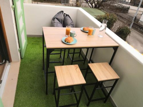 a table and chairs on a balcony with food and orange juice at Superbe Loft industriel - Casa Vostra - CAUTION 800 EUR & ID requises - Gaillard Tram-Frontière in Gaillard