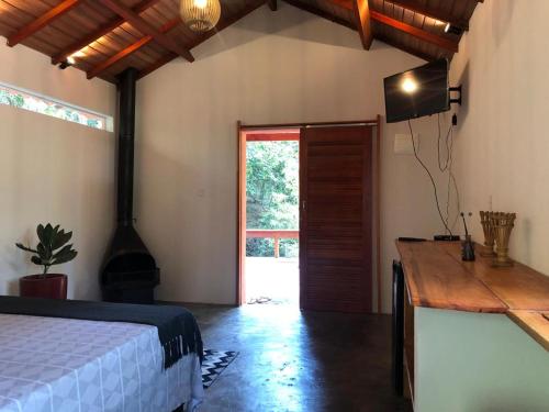 a bedroom with a bed and a tv and a door at Pousada Chalés da Lua in Munhoz