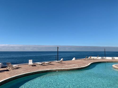 a swimming pool with a view of the ocean at Beachfront Condo close Puerto Nuevo, Papas, and Valle de Guadalupe in Rosarito