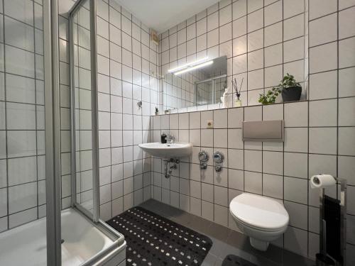 a white tiled bathroom with a toilet and a sink at Einzigartiges Apartment in toller Altstadt by Rabe - free Netflix & Coffee-Bar in Karlsruhe