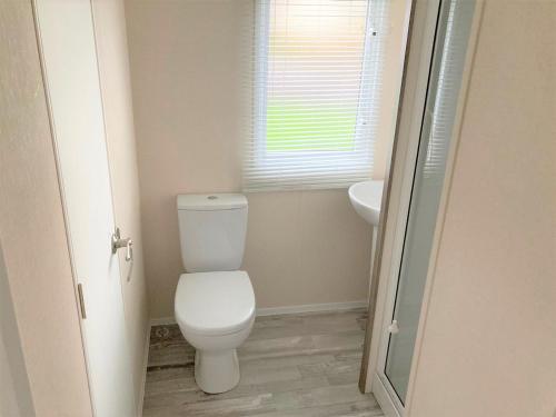 uma casa de banho com um WC branco e um lavatório. em 3 Bedroom Modern Caravan Sleeps up to 8 em Millom
