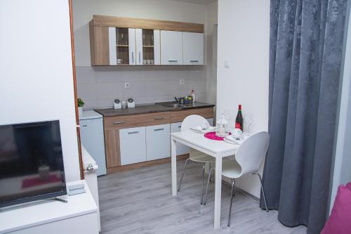a small kitchen with a white table and chairs at Family Apartmani Le in Leskovac