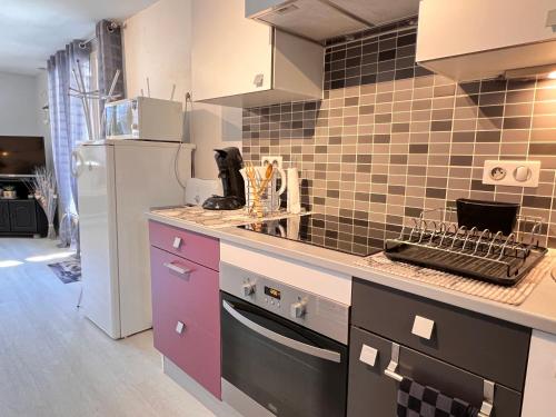 - une cuisine avec des placards violets et un réfrigérateur dans l'établissement T2 ensoleillé. Terrasse, jardin commun, vue, parking., à Cauterets