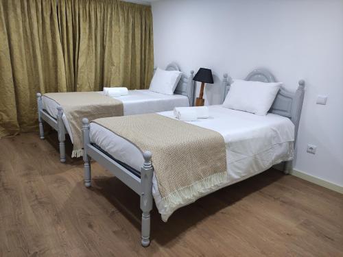 two beds sitting next to each other in a room at Quinta de Esteves - Lake House Suites in Ponte de Lima