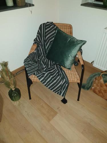 a chair with a green pillow and a blanket at La Mara Élo in Sart-lez-Spa