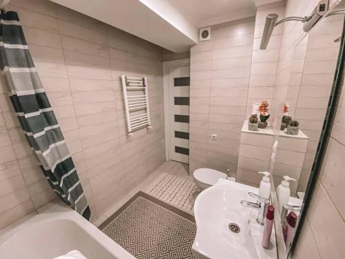Un baño con lavabo, bañera e inodoro. en Sweet Home Apartment, en Chişinău