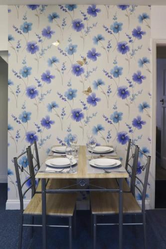 a dining table with blue flowers on a wall at Entire Family Vacation Home . WiFi . FREE Parking in Beeston