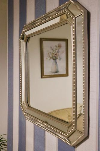 a mirror hanging on a wall with a vase of flowers at Entire Family Vacation Home . WiFi . FREE Parking in Beeston