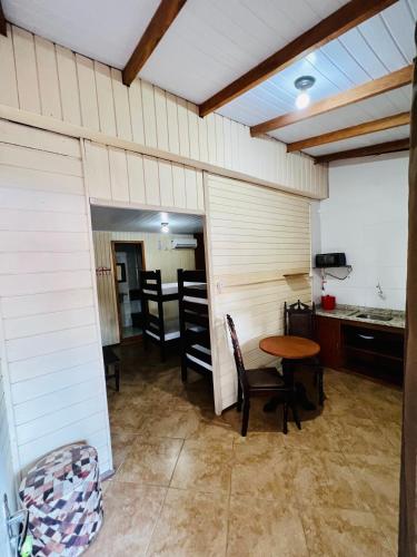 a room with a table and chairs and a kitchen at Pousada Rosa Center in Praia do Rosa