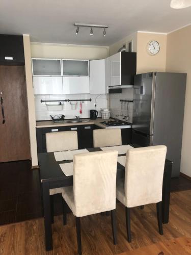 a kitchen with a black table and white chairs at Apartament Elbląg Wyczółkowskiego 10 in Elblag