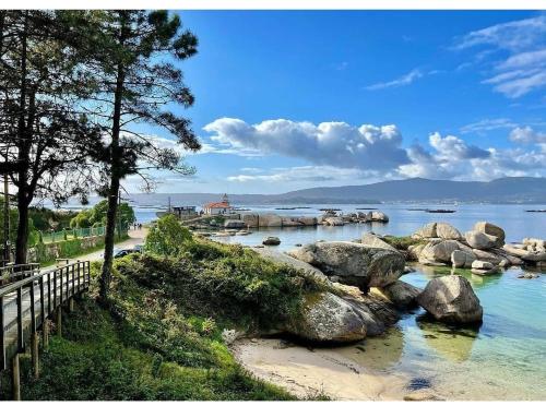 a body of water with rocks and trees on the shore at Casa Guillan Illa de Arousa in Isla de Arosa
