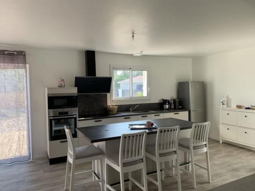 a kitchen with a table and chairs in a kitchen at VillasHomeClet - Villa Les Alizés in Vensac