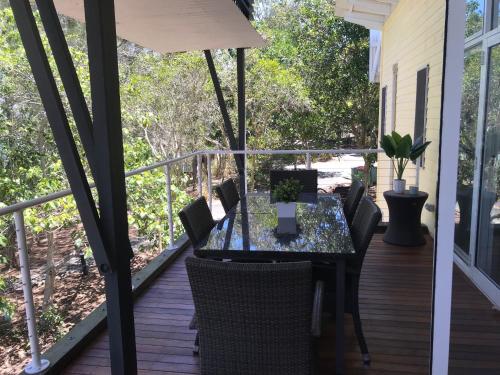 a glass table and chairs on a deck at Couran Cove Resort Private Apartments, South Stradbroke Island, Gold Coast in South Stradbroke