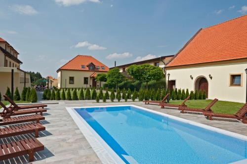 a swimming pool in a yard with benches and a house at Hotel Buchlov in Buchlovice