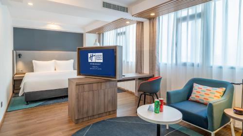 a hotel room with a bed and a tv at Holiday Inn Express Qingdao City Center by IHG in Qingdao