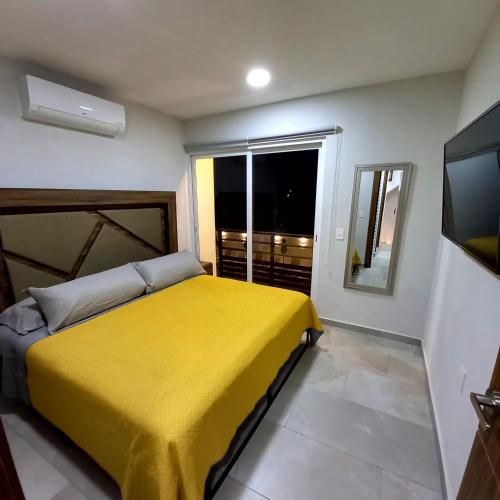 a bedroom with a yellow bed and a television at Villas Frida Kahlo in Bucerías