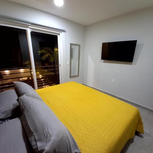 a bedroom with a yellow bed and a window at Villas Frida Kahlo in Bucerías
