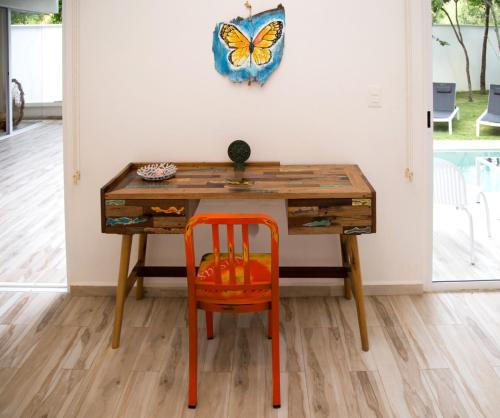 a desk with a orange chair and a butterfly on the wall at Luxury Private Villas , Private Pool, Private garden, Jacuzzi, 24hours security in Tulum