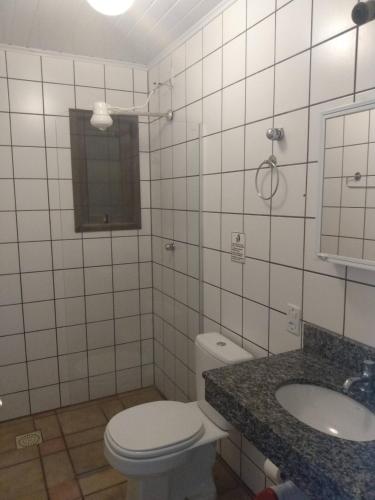 a bathroom with a toilet and a sink and a mirror at Condominio Sargento Laranja in Garopaba