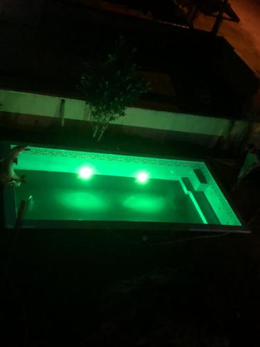 a green swimming pool with lights in the dark at Apartamento encantador in Itapoa
