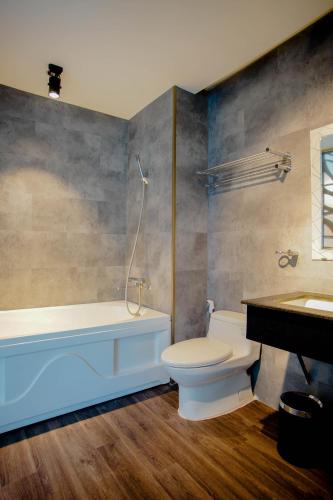 a bathroom with a tub and a toilet and a sink at Lá Hotel Bình Tân in Ho Chi Minh City