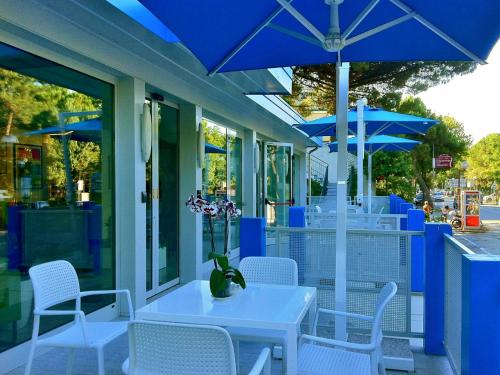 - une table et des chaises avec des parasols bleus sur la terrasse dans l'établissement Hotel Bermuda, à Marina di Ravenna