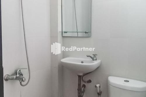 a bathroom with a sink and a mirror and a toilet at Ardico Residence Syariah Mitra RedDoorz in Poponcal 2