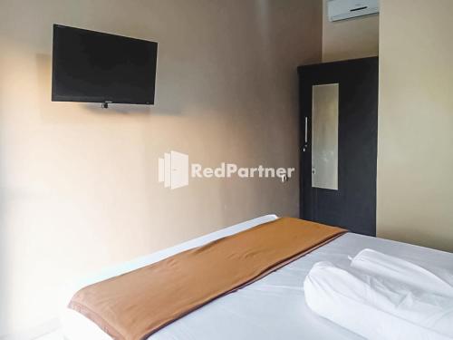 a bedroom with a bed with a flat screen tv on the wall at Ardico Residence Syariah Mitra RedDoorz in Poponcal 2