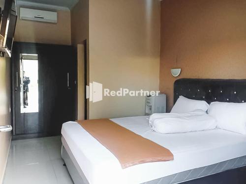 una camera da letto con un grande letto con cuscini bianchi di Ardico Residence Syariah Mitra RedDoorz a Poponcal 2
