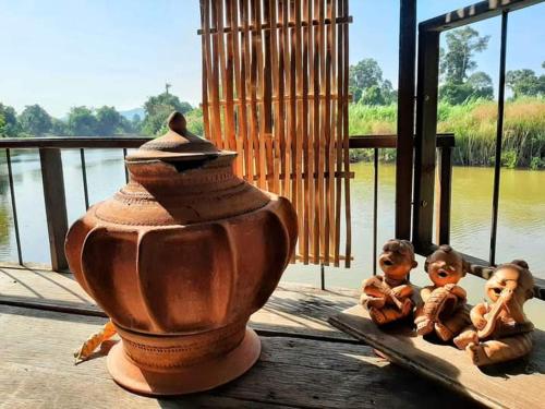 dos pequeñas estatuillas están sentadas junto a un jarrón. en Rustic​ Charm​ Suphan​, en Ban Tha Pong