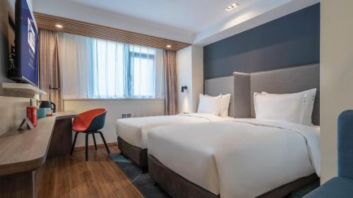 a hotel room with two beds and a desk at Holiday Inn Express Qingdao City Center by IHG in Qingdao