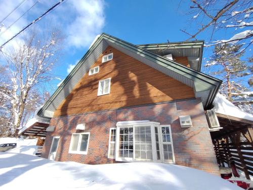 a brick house with snow in front of it at Keimichi Guest House in Hakuba