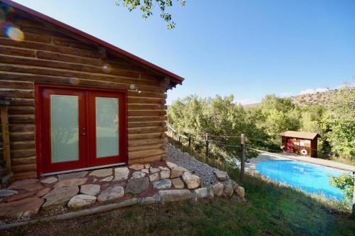 a log cabin with a swimming pool next to a house at Pack Creek ~ Ranch House in Moab
