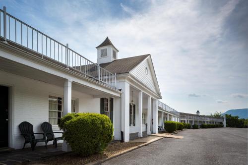 a white building with two chairs on a street at Luray Caverns Motels in Luray