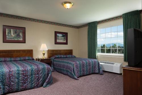 una camera d'albergo con due letti e una televisione di Luray Caverns Motels a Luray