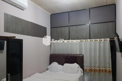 1 dormitorio con cama y cortina en Homestay Lotus Bangka Mitra RedDoorz, en Pangkalpinang