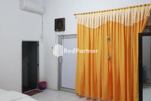 cortina de ducha naranja en una habitación con ventana en Homestay Lotus Bangka Mitra RedDoorz en Pangkalpinang