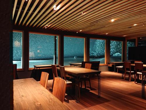 a dining room with tables and chairs and windows at kamosu mori in Tokamachi