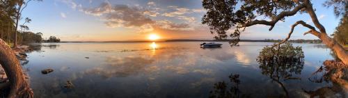 a boat in the middle of a lake at sunset at Premium Waterfront - Jervis Bay Area in St Georges Basin