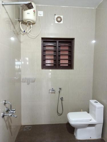 a bathroom with a toilet and a window and a shower at Beach Nest in Kannur